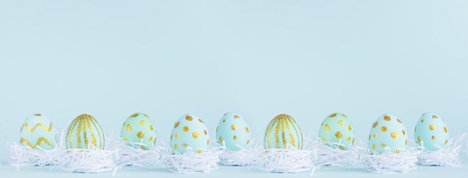 Stylish easter banner - blue easter eggs with gold design in white nest in row on blue background.