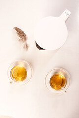 Two mugs of herbal tea and teapot on white. Top view. Concept of good morning, easy start to day