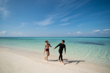 Couple holding hands and walk on the beach enjoying beautiful summer holiday vacation. Travel vacation lifestyle concept