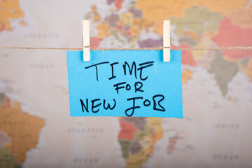 Time for new job word written on a Blue color sticky note hanging with a wire in front of world map background