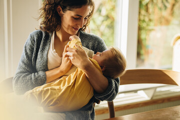 Caring mother feeding milk from bottle to her baby