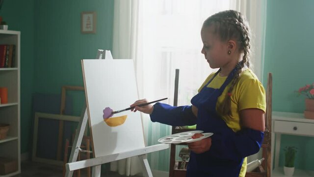 Talented small girl, little artist, is staying home and practices painting, focused and hard-working makes efforts to improve painting skills, Slow motion.