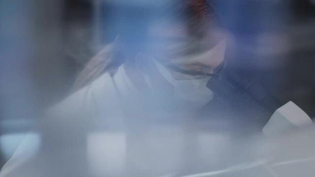 Female doctor working in laboratory. Studying medical samples. Looking through glassware and monitor