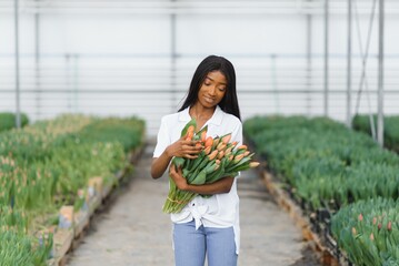 close up of african american woman holding flowers in greenhouse