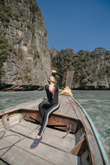 Woman sitting in the front of a longtail boat at sea in Pileh Lagoon Andaman sea, Phi Phi Islands, Thailand.