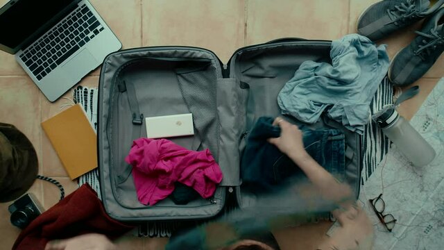 Top view on stressed and anxious traveller unpack suitcase, throw clothes out of travel bag. Make mess in apartment, worried, search for lost missing object. Happy unpacking to start holidays