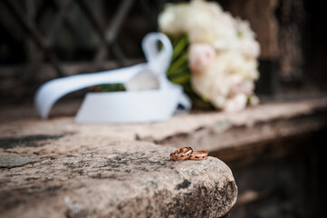 Wedding rings on a stone, a bouquet of pink flowers