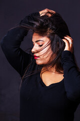 High contrast fashion photo of an Indian girl posing with flowing hairs for modeling photo shoot in studio against gray background