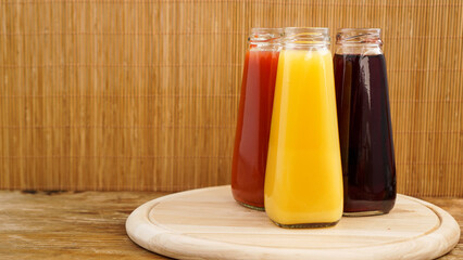 Glass bottles of fresh healthy juice on wooden background. Multi-colored juices.