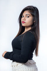 3 by 4 length photo of an Indian girl wearing black topper and short white skirt  posing sideways for modelling photo shoot in studio against white background