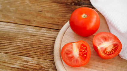 Whole and cut tomato on a wooden board for slicing. Rustic style and wood