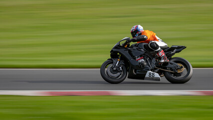 A panning shot of a racing motorbike as it circuits a track.