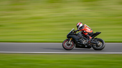 Fototapeta na wymiar A panning shot of a racing motorbike as it circuits a track.