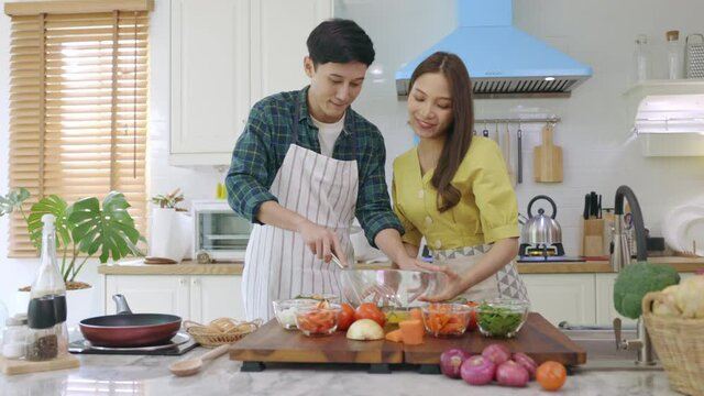 Newly married couple Help each other cook happily, having fun at home. Couples spend time together making lovely, happy meals.