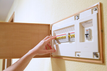 Woman hand turning off fuse box in the house. Selective focus..