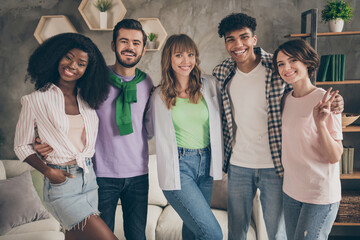 Fototapeta premium Photo portrait of friends embracing together in room showing v-sign gesture smiling