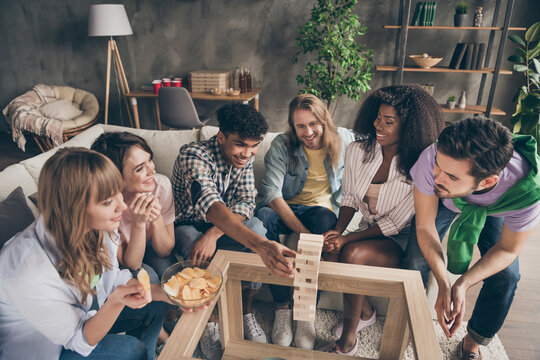 Photo portrait of friends playing game wooden blocks eating chips laughing excited on weekend