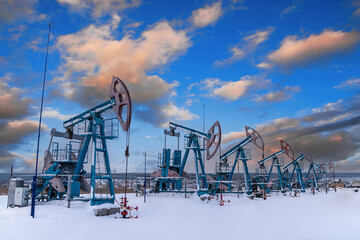 Several Oil pumpjack under the blue sky with clouds winter working. Oil rig energy industrial...