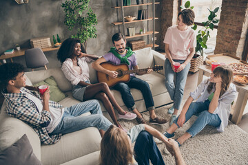 Photo portrait of funny students sitting on sofa in hostel eating pizza playing guitar spending time together drinking beer