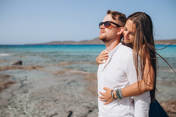 Portrait of a woman embracing her man from behind on seaside background