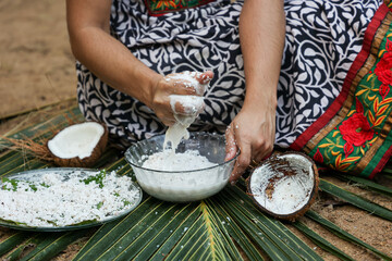 Woman making homemade fresh thick coconut milk with grated coconut , squeezing with hand  Kerala India Sri Lanka in Indian Kitchen. ingredient in Indian curry. vegan non dairy health drink.