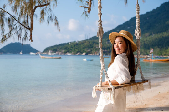 Portrait image of a beautiful young asian woman with swing by the sea