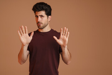 Displeased unshaven young man showing stop gesture at camera
