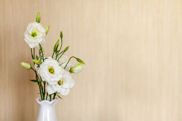 White flowers Eustoma or Lisianthus in vase on wooden background with copy space