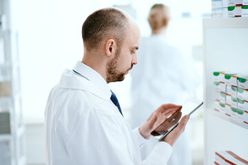 pharmacist scrolling on digital tablet checking medication .