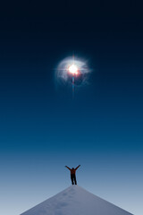 Fototapeta na wymiar Silhouette of a man on snowy hill looking up and celebrating the bright star on the sky. The star in the image furnished by NASA.