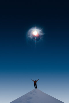 Silhouette of a man on snowy hill looking up and celebrating the bright star on the sky. The star in the image furnished by NASA.