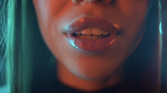 girl's mouth close up, moving her lips and talking in neon lights. Soft focus, blur. Concept of a look of a man under the influence of alcohol or drugs.