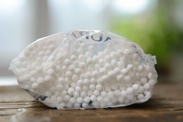 On an old board is a package of ear sticks. Close-up. In the background, indoor plants and a window. Concept - nature conservation