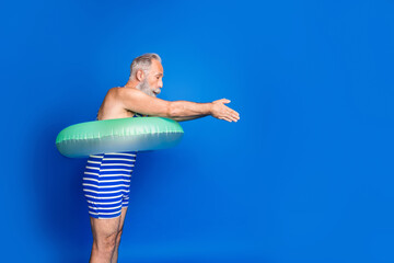 Profile photo of optimistic grey beard man jump wear lifebuoy blue swimsuit isolated on blue background