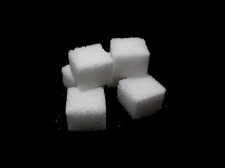 Lump sugar cubes on black background, isolated cubes of white sugar on black background