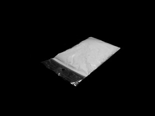 Cocaine drug powder in bag on black background