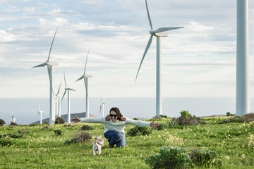 Smiling woman playing with dog in meadow with windmills