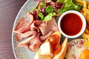 English Breakfast including ham, egg with bacon, french fries and vegetables