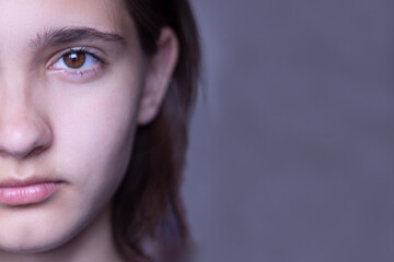 Fototapeta premium Half the face of a beautiful young brunette girl with dark brown eyes and thick eyebrows. Bob haircut, short hair. Close-up.