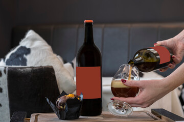 Bottle of cherry ale, chocolate muffin on a wooden tray, a female hand pours beer from a bottle into a glass
