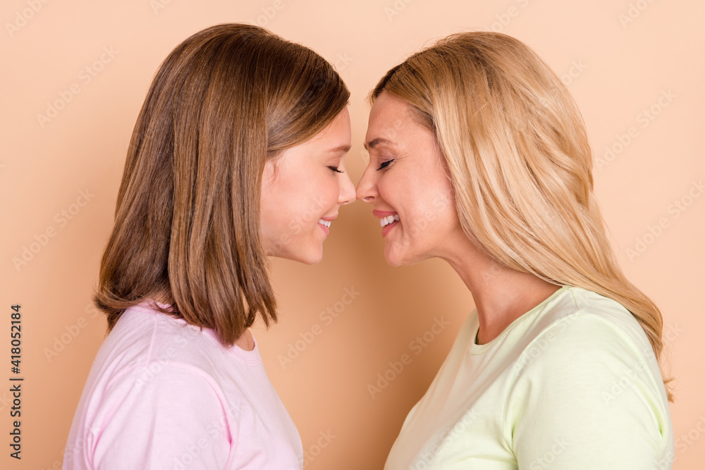 Poster profile side photo of happy charming mother and daughter touch noses smile isolated on beige color b