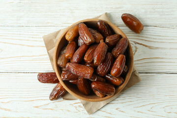 Bowl with dried dates on paper on white wooden table