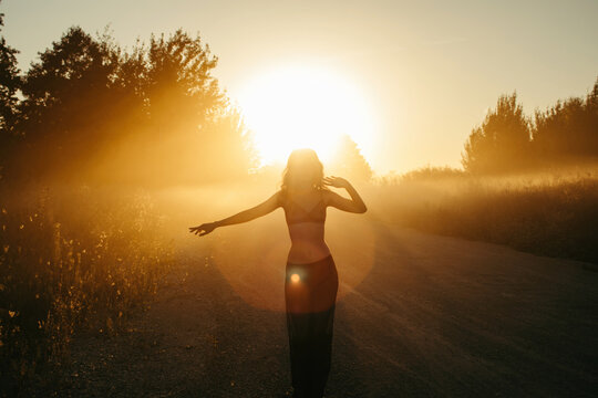 Silhouette of a woman dancing by a road at sunset, Russia