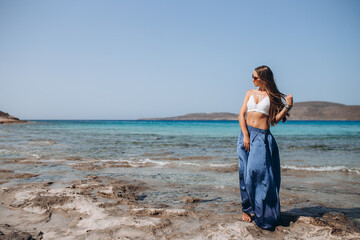 Fototapeta na wymiar gorgeous style brunette young woman in blue chameleon dress long train standing on a rock near the sea, sand tropical on a rock.beautiful mermaid lonely melancholy waiting freedom and freelancing