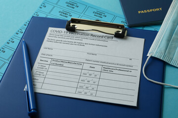 Covid - 19 vaccination concept with record card, mask and passport on blue background