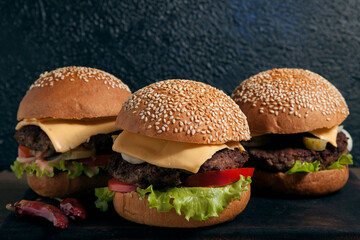 Group of cheeseburgers on wooden board on dark background