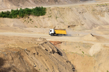 Dump truck transports sand in open pit mine. In the production of concrete, concrete for the construction using coarse sand. Quarry in which sand and gravel is excavated from ground. Mining industry