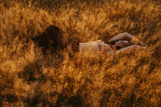 Woman lying in a field in summer at sunset, Russia