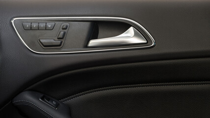 Naklejka premium Modern car door handle with seat control knobs.