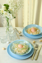 Happy Easter table setting with eggs on white textured table